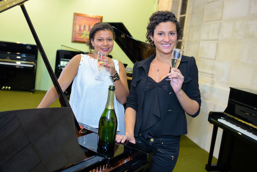Two ladies enjoying a wine while playing piano